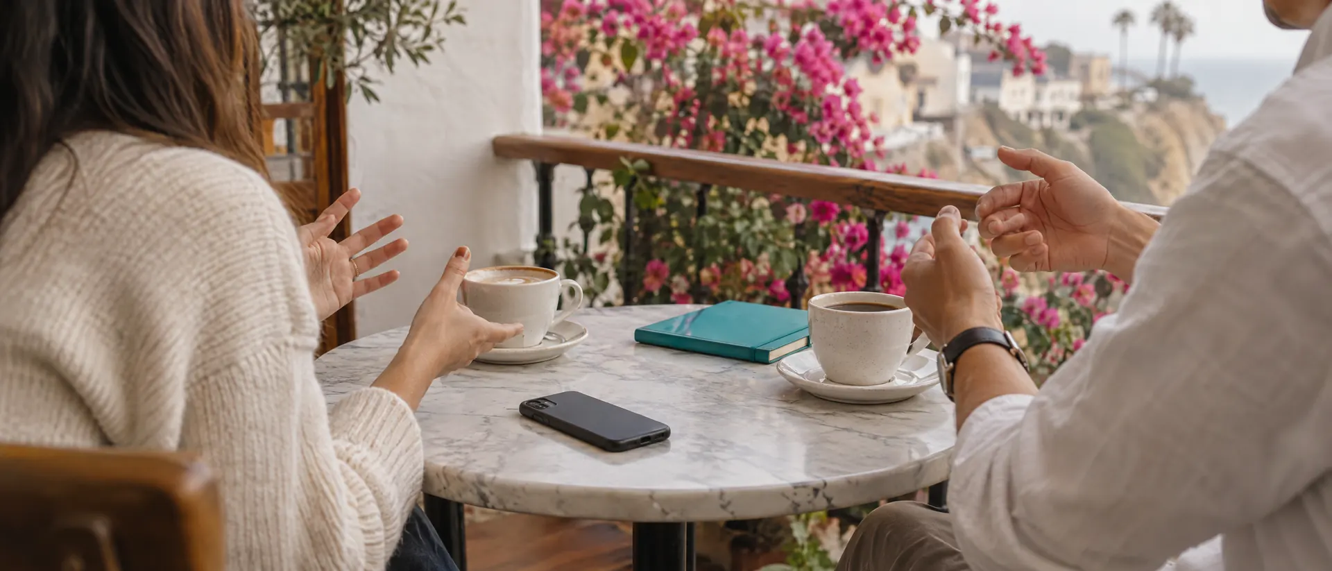 Mesa de café en una terraza de Barranco con dos tazas, un celular y una libreta turquesa